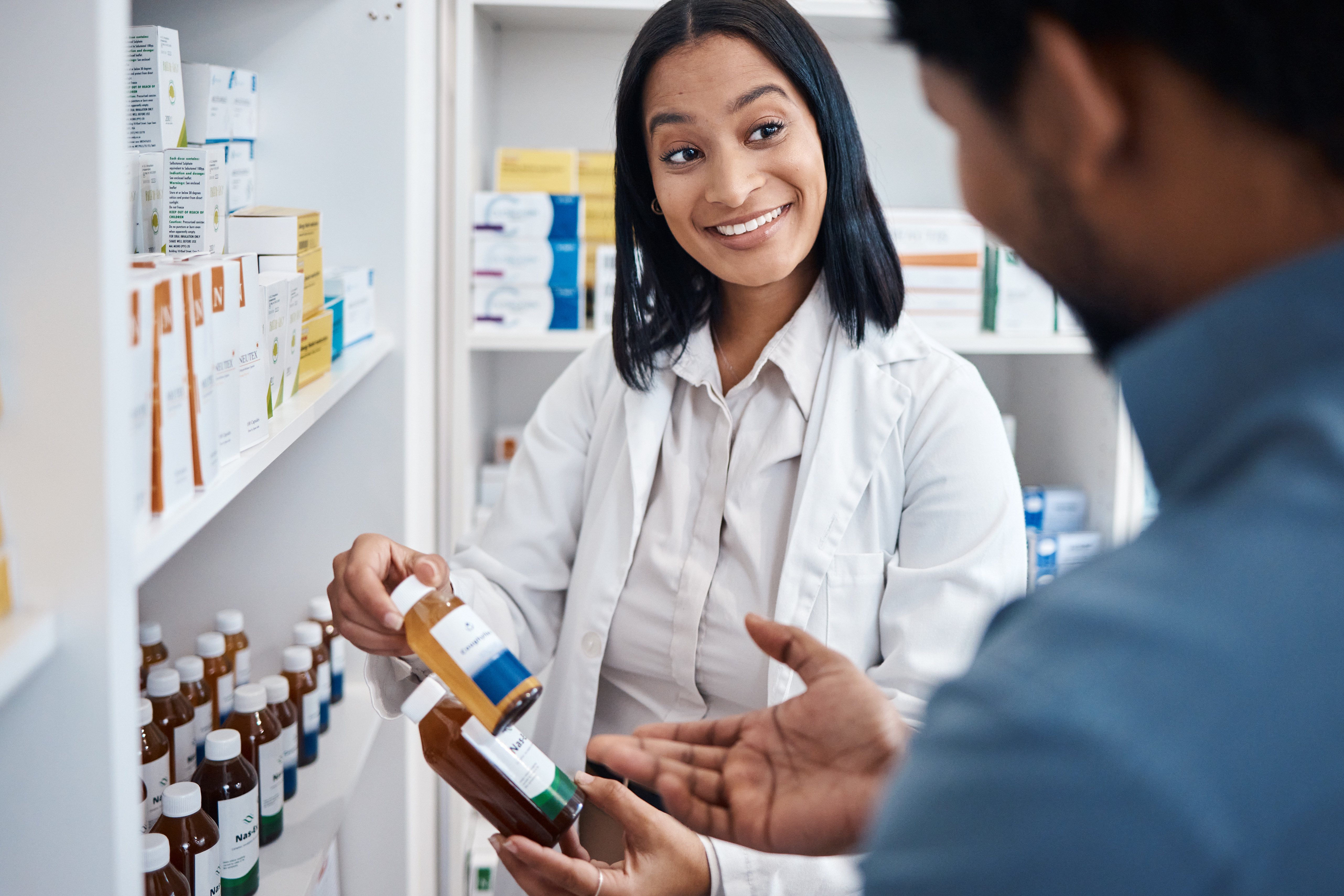 Pharmacist showing a customer prescription bottles