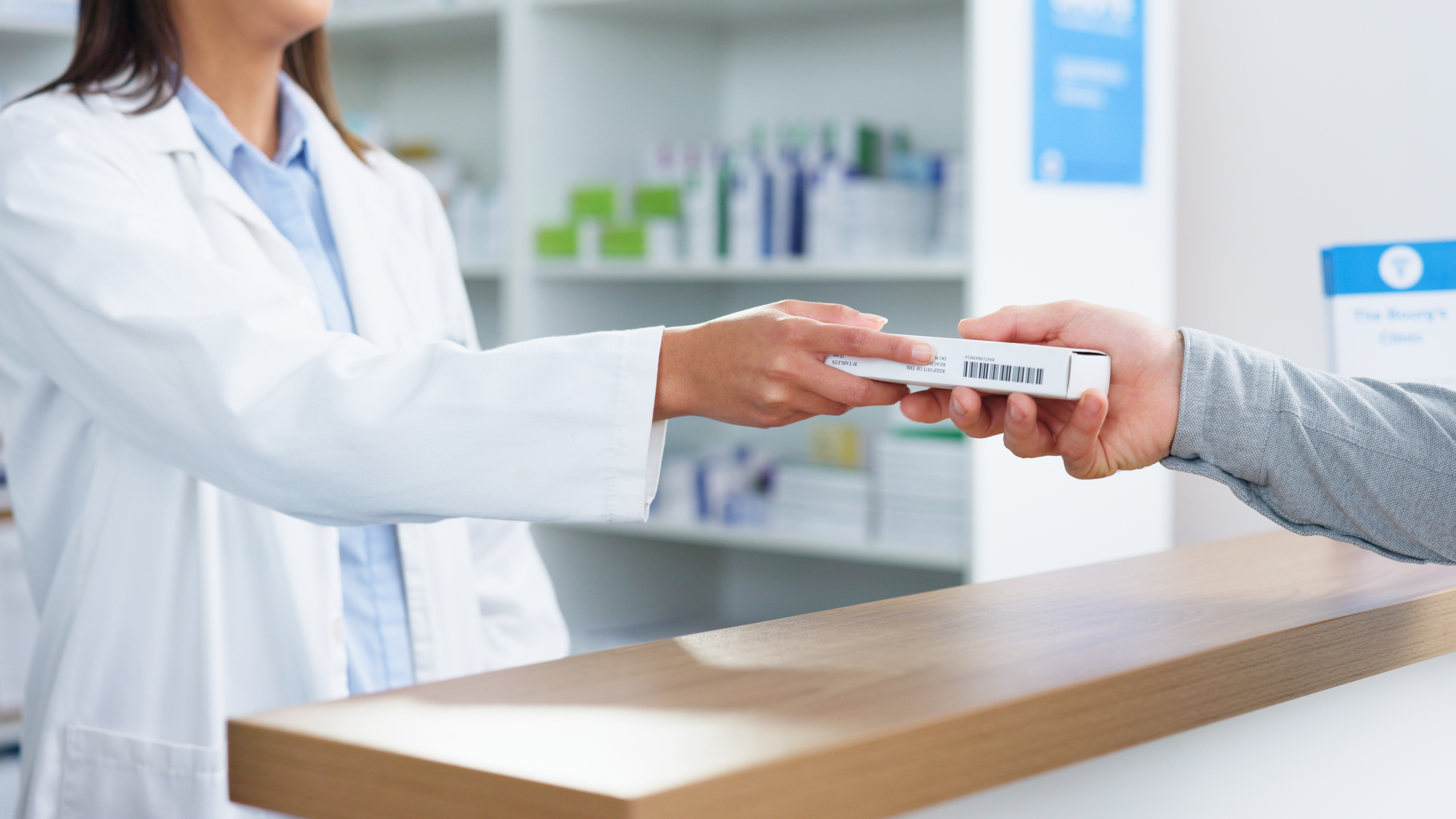 Pharmacist hands prescription to customer