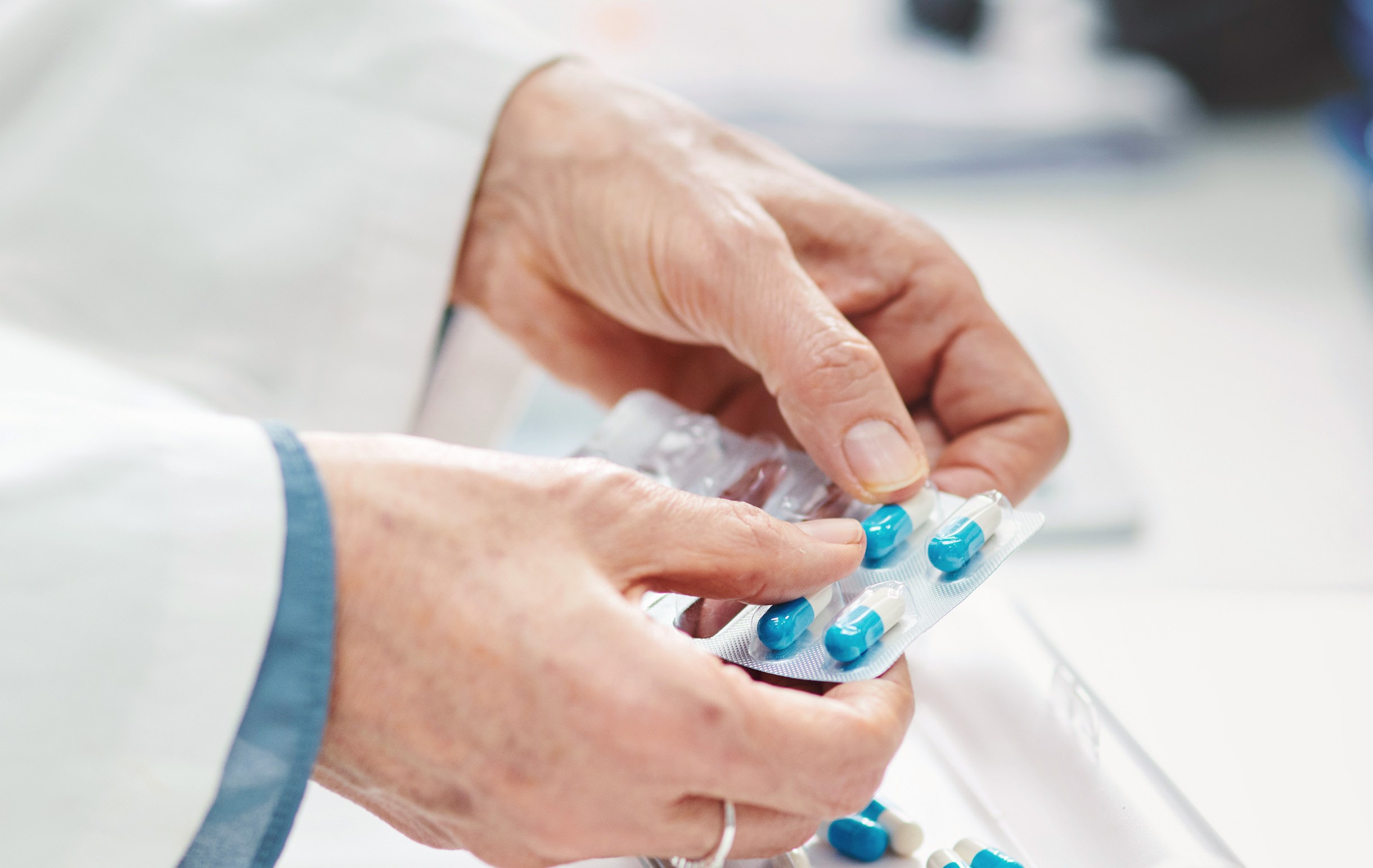 Pharmacist popping capsules out of pill pack