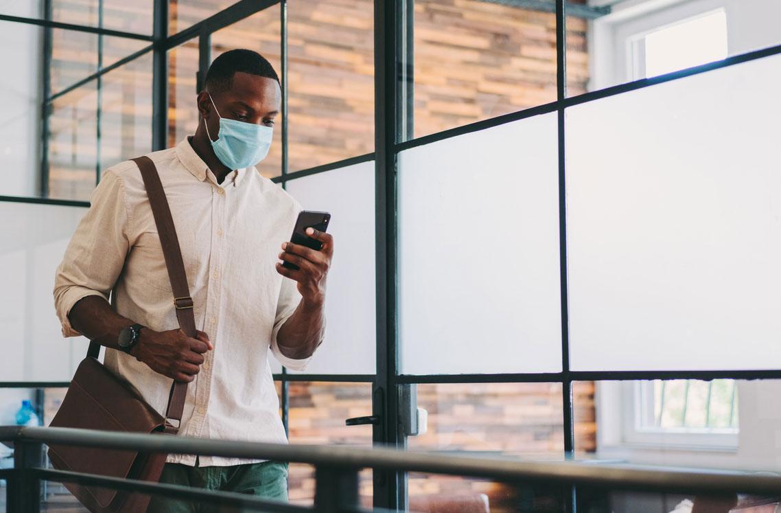 Man wearing face mask and looking at phone