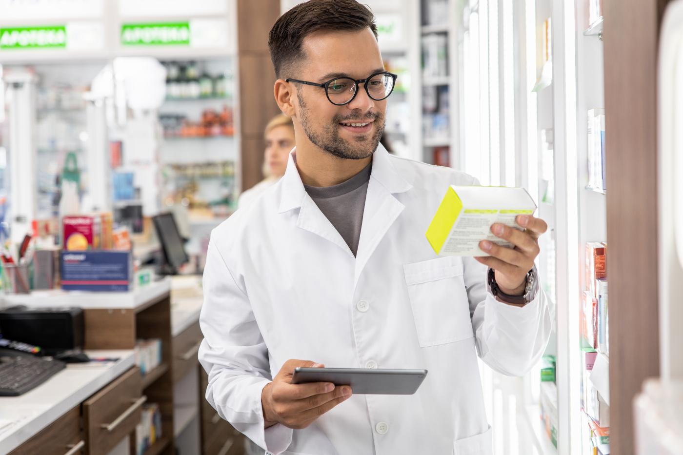 Pharmacist looks at and holds small box in left hand