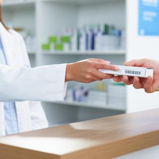 Pharmacist hands prescription to customer