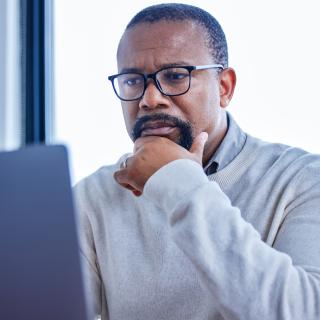 Man with a concerned facial expressions sitting at laptop